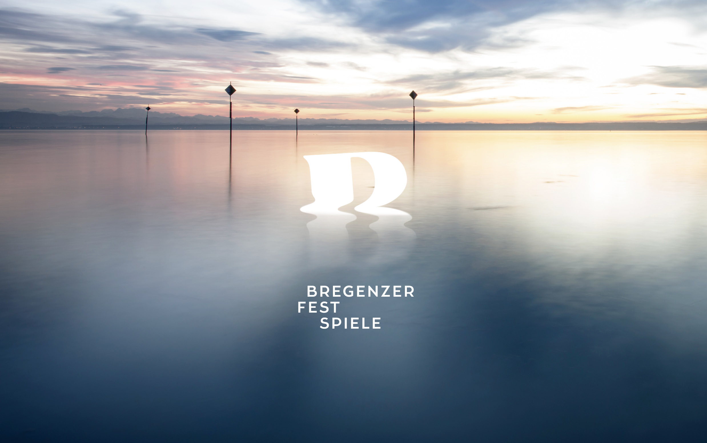 Seebühne Bregenz mit dem Logo der Bregenzer Festspiele und dem Bodensee im Hintergrund bei Sonnenaufgang.